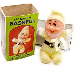 Puede incluir: Una muñeca vintage del enano Tímido de Blancanieves y los Siete Enanitos. La muñeca es amarilla con barba blanca, cinturón negro y cinta blanca. La caja dice "MY NAME IS BASHFUL" y "I AM ONE OF SNOW WHITE'S DWARFS".