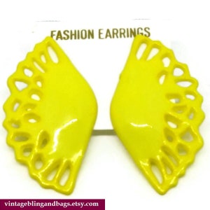 May include: A pair of yellow, fan-shaped earrings with a cutout design. The earrings are labeled "FASHION EARRINGS".