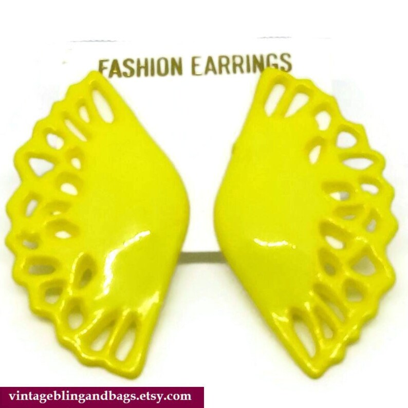 May include: A pair of yellow, fan-shaped earrings with a cutout design. The earrings are labeled "FASHION EARRINGS".