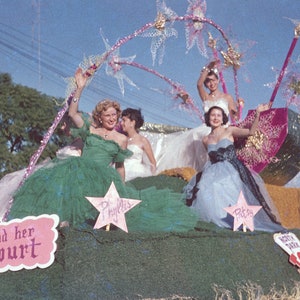 May include: Four women in formal dresses stand on a float decorated with pink and green stars. The float is decorated with a pink and green watermelon. The women are smiling and waving. The sign on the float reads "And her Court".