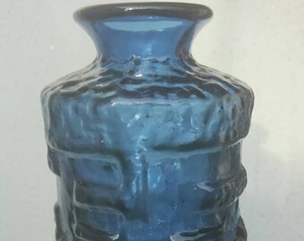 May include: A blue glass vase with a textured surface. The vase has a wide mouth and a narrow neck.