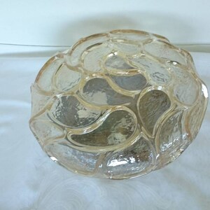 May include: A clear glass lampshade with a textured, wavy design. The shade is round and has a slightly frosted appearance.