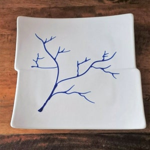 Op de afbeelding: Een wit vierkant keramiek bord met een blauw boomtak ontwerp.
