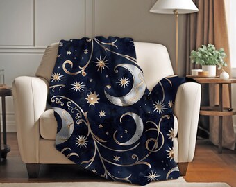 May include: A navy blue throw blanket with a gold and white moon and star pattern. The blanket is draped over a white armchair.