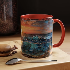 May include: A ceramic coffee mug with a vibrant ocean sunset design. The mug has a red handle and interior, with a detailed illustration of waves and a sunset. The design is reminiscent of stained glass.