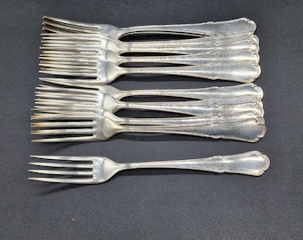 Peut inclure: Un ensemble de fourchettes argentées disposées sur une surface sombre. Les fourchettes présentent un design classique avec des dents et des manches décoratifs. L'image présente un ensemble de couverts, idéal pour les repas formels ou les occasions spéciales.