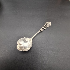 Puede incluir: Una cuchara de plata con un diseño floral ornamentado en el cuenco y un mango decorativo.