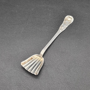 May include: A silver salt spoon with a fluted bowl and a decorative handle. The handle has a floral design and the inscription "STERLING".