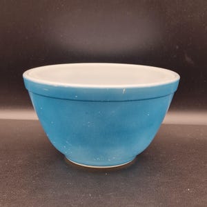 Peut inclure: Un saladier en céramique turquoise avec un intérieur blanc. Le bol a une forme arrondie et un bord légèrement évasé. L'extérieur a un aspect moucheté. Cet article de cuisine est adapté à la pâtisserie et à la préparation des aliments.