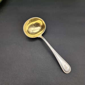 以下が含まれることがあります： 金メッキのボウルが付いた銀のスプーン。ハンドルはビーズ模様で飾られており、刻まれたモノグラムがあります。