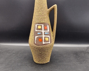 Könnte beinhalten: Eine braune Keramikvase mit strukturierter Oberfläche und einem geometrischen Muster in Gelb-, Rot-, Blau- und Weißtönen.