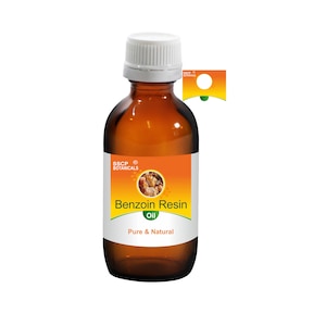 May include: A brown glass bottle with a white cap, labelled "Benzoin Resin Oil, Pure & Natural" with a yellow and orange label featuring the text "SSCB Botanicals" and a picture of benzoin resin.