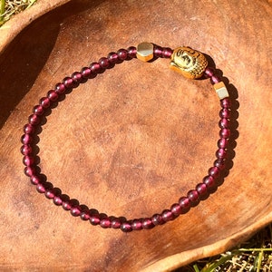 Garnet Crystal Bracelet featuring a Buddha Charm and gold spacers.