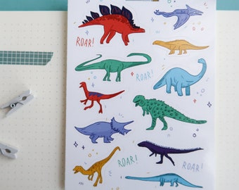 Op de afbeelding: Een vel met kleurrijke dinosaurus stickers met het woord "IMAGINATION" bovenaan. De stickers tonen verschillende dinosaurussen in verschillende kleuren, waaronder rood, groen, blauw, geel en paars. Het woord "ROAR!" staat meerdere keren op het vel.