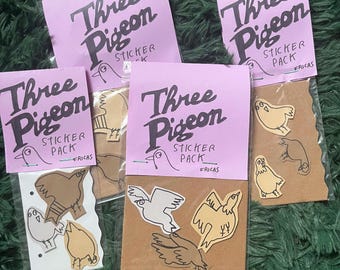 May include: Multiple sticker packs featuring the text "Three Pigeon" on pink cards. The packs contain pigeon-themed stickers in different colors and poses, presented in clear plastic packaging.