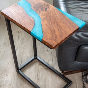 May include: A wooden end table with a black metal frame. The tabletop features a blue resin river design.