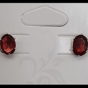 Peut inclure: Une paire de boucles d'oreilles en argent avec des pierres précieuses rouges de forme ovale.