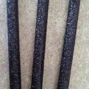 K&ouml;nnte beinhalten: Drei schwarze St&auml;be mit glitzernder Oberfl&auml;che. Die St&auml;be sind etwa 30 cm lang und vertikal angeordnet.