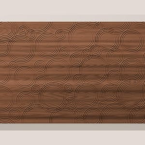 May include: A rectangular wooden wall panel featuring a carved, three-dimensional pattern of concentric circles that mimic the appearance of ripples on a water surface. The natural brown wood grain is visible across the entire surface.