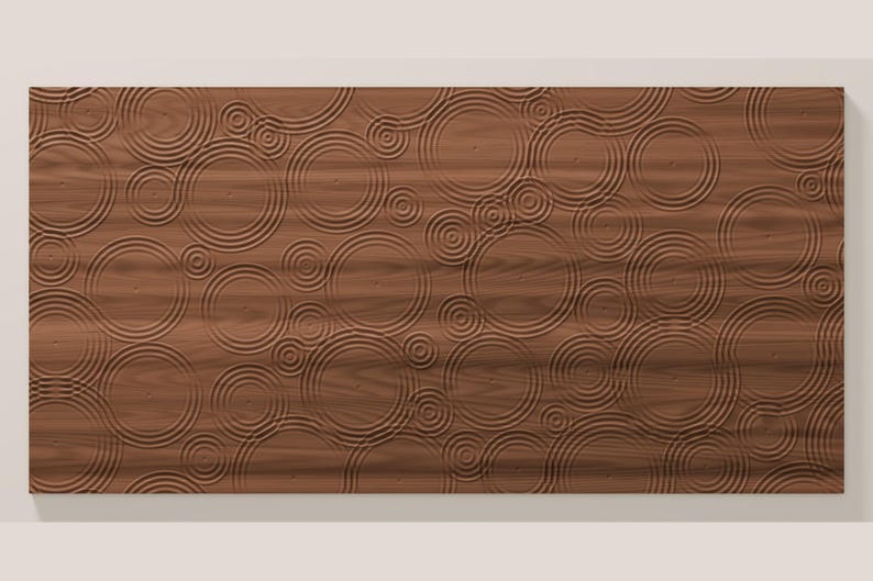 May include: A rectangular wooden wall panel featuring a carved, three-dimensional pattern of concentric circles that mimic the appearance of ripples on a water surface. The natural brown wood grain is visible across the entire surface.