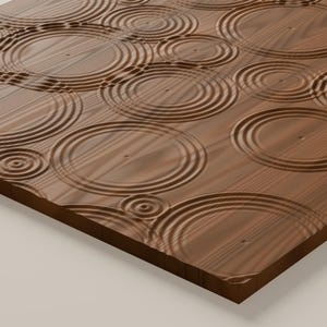 May include: A rectangular wooden panel featuring a carved surface texture of concentric circles that mimic the appearance of ripples in water. The wood grain is visible throughout the brown surface, with varying sizes of circular indentations.