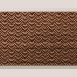 May include: A rectangular brown panel featuring a repeating embossed pattern of overlapping semicircles. The design consists of multiple rows of concentric arcs that create a textured, wave-like appearance across the entire surface of the object.