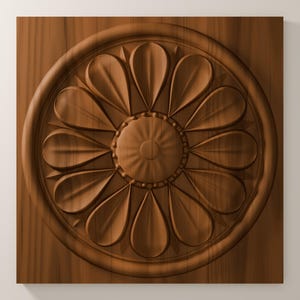 May include: A square wooden panel featuring a carved circular medallion in the center. The medallion displays a symmetrical floral pattern with twelve rounded petals radiating from a small, textured, circular hub, all in a warm brown tone.
