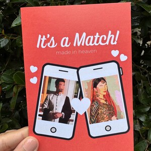 May include: A red card with the text "It's a Match! made in heaven" and two white hearts. The card features two phone screens with images of a man and a woman, each with a white heart between them.