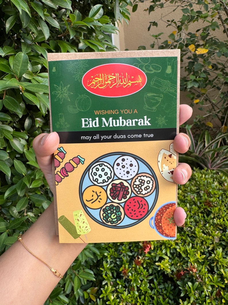 May include: A greeting card with the text "Eid Mubarak" and a colorful illustration of various dishes. The card has a green and tan color scheme, with Arabic script at the top. The phrase "may all your duas come true" is also included.