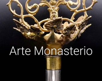 May include: A gold-toned metal staff with a crown of thorns design and a sculpted image of Jesus Christ. The staff is 30 inches by 18 inches and has the text "Arte Monasterio" on it.