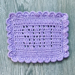 May include: A lavender crocheted square dishcloth with a scalloped edge.