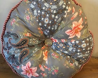 Cuscino rotondo patchwork fatto a mano nei colori grigio, rosa e beige.