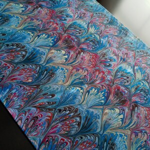 May include: A blue, red, and white marbled fabric with a peacock feather design.