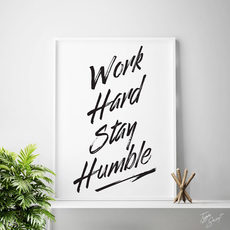 Puede incluir: Impresi&oacute;n tipogr&aacute;fica en blanco y negro con el texto "Work Hard Stay Humble" en una fuente en negrita con trazos de pincel.