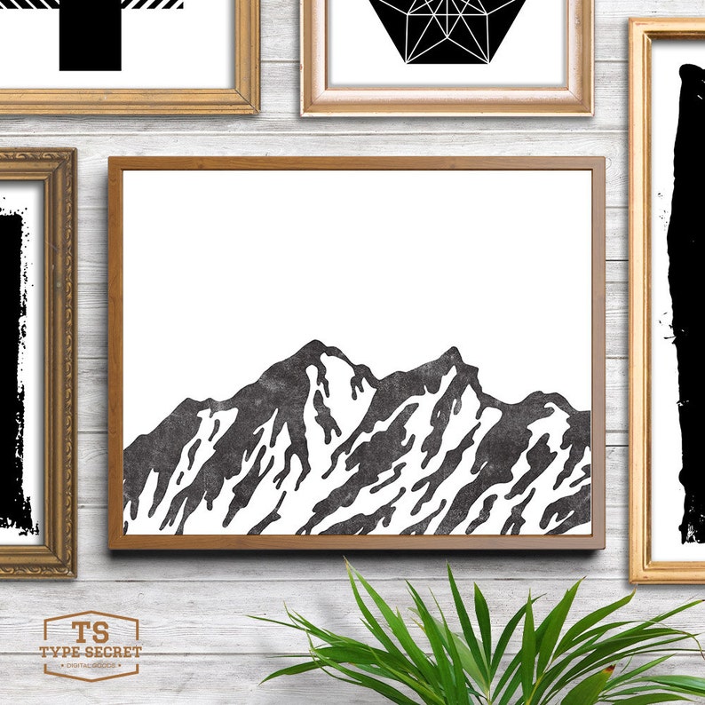 May include: Black and white illustration of a mountain range with a textured look. The image is framed in a brown wood frame.