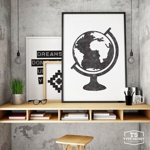 May include: A wooden shelf unit with three shelves, each containing books. The shelf is mounted on a gray concrete wall. There are two black framed prints above the shelf, one with a globe and the other with the text "DREAMS DON'T" and a geometric pattern.