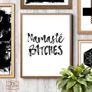Puede incluir: Una impresi&oacute;n enmarcada con fondo blanco y texto negro que dice "Namaste Bitches". La impresi&oacute;n est&aacute; en un marco marr&oacute;n y est&aacute; colgada en una pared blanca.