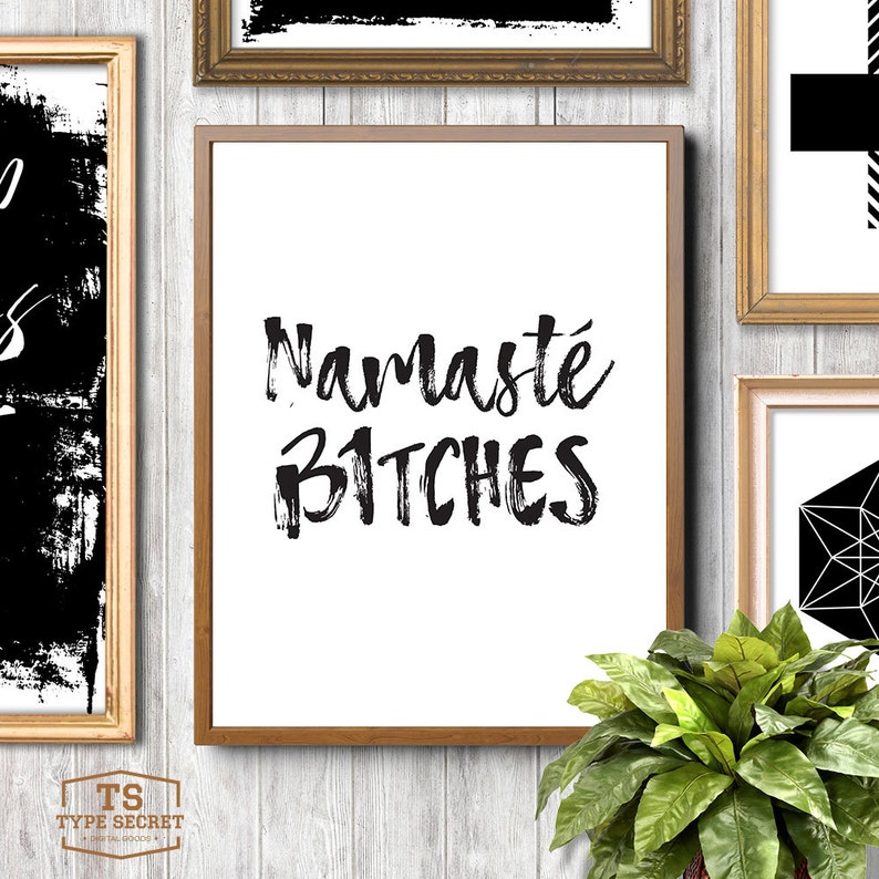 Puede incluir: Una impresi&oacute;n enmarcada con fondo blanco y texto negro que dice "Namaste Bitches". La impresi&oacute;n est&aacute; en un marco marr&oacute;n y est&aacute; colgada en una pared blanca.