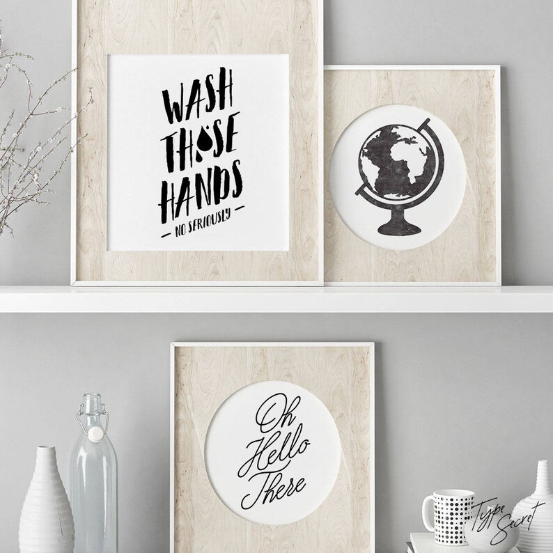 May include: Three framed prints with black and white text and illustrations. The top left print says "Wash those hands - No seriously -." The top right print has a black and white illustration of a globe. The bottom print says "Oh Hello There".