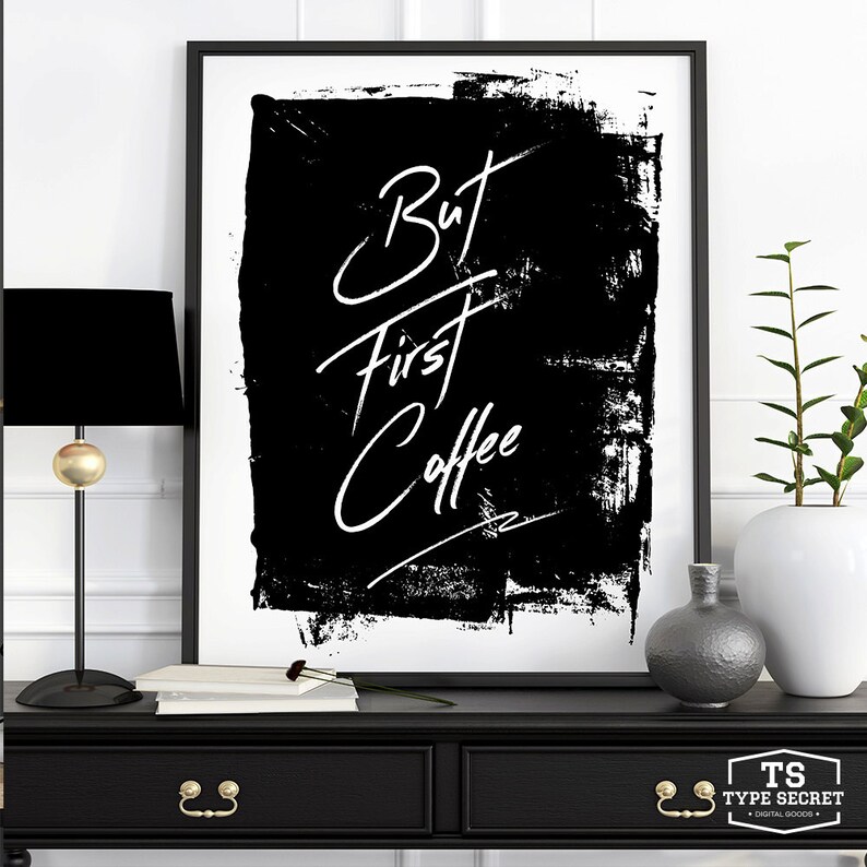May include: Black and white art print with the text "But first coffee" in a white handwritten font on a black background with a white border.