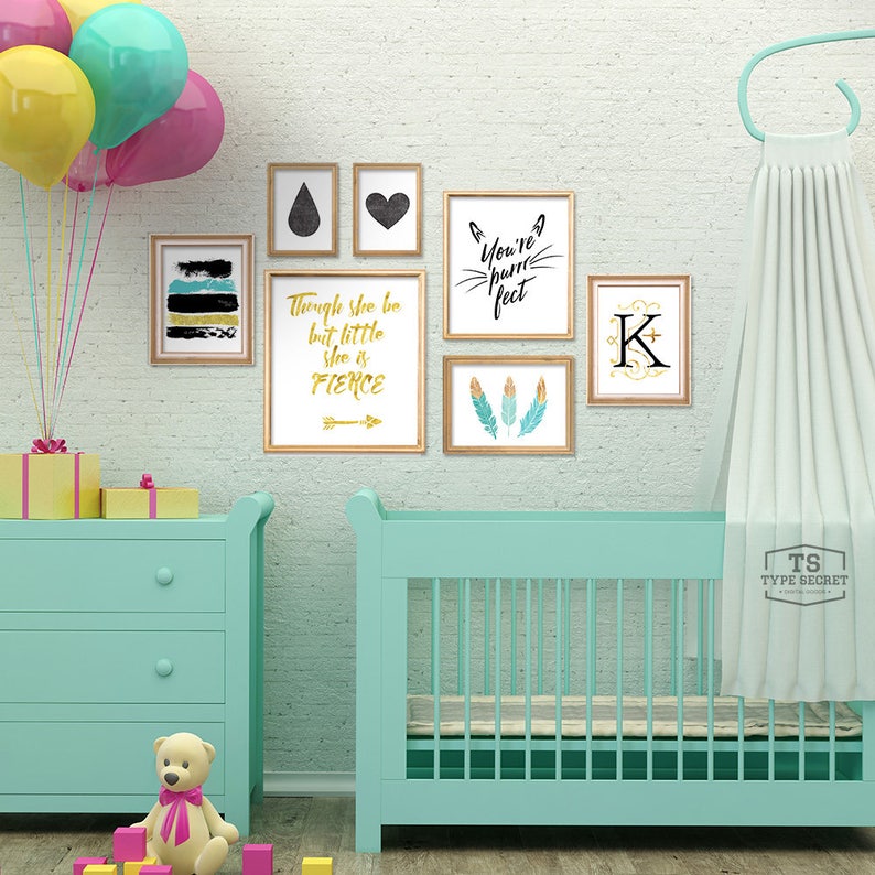 K&ouml;nnte beinhalten: Ein hellblaues Babybett mit einem wei&szlig;en Baldachin, eine hellblaue Kommode mit drei Schubladen und ein gelber, rosa und blauer Ballonstrau&szlig;. Die Wand ist mit gerahmten Drucken dekoriert, die ein schwarzes Herz, eine schwarze Tr&auml;ne, ein schwarz-wei&szlig;es abstraktes Design, einen goldenen Pfeil mit dem Text "Though she be but little she is fierce", ein schwarz-wei&szlig;es Katzen Gesicht mit dem Text "You're pawfect" und einen goldenen Buchstaben K zeigen.
