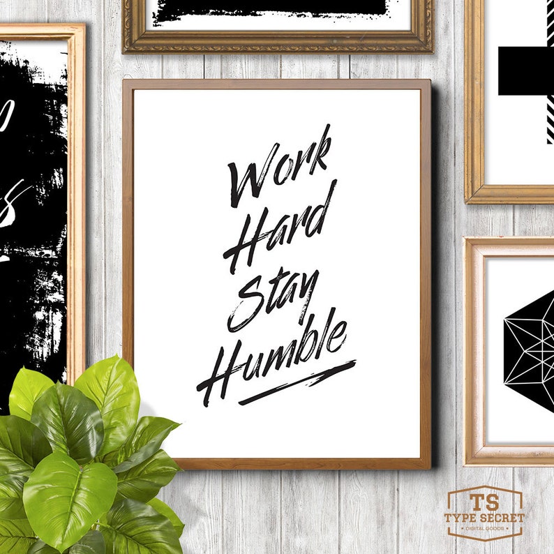 Puede incluir: Una cita motivacional en blanco y negro en un marco negro sobre fondo blanco. La cita dice "Trabaja duro, mantente humilde".