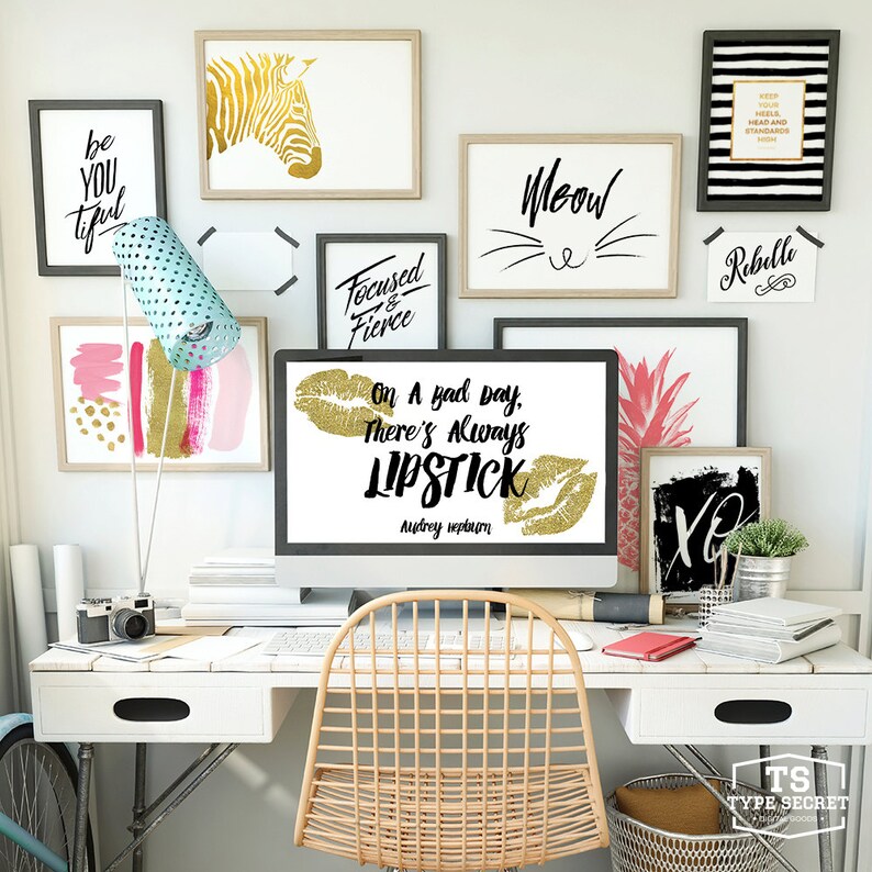 Puede incluir: Un escritorio blanco con un monitor de computadora que muestra una cita sobre el l&aacute;piz labial. La cita dice "On a bad day, there's always lipstick." de Audrey Hepburn. El escritorio tiene una silla blanca, una c&aacute;mara, una pi&ntilde;a y otra decoraci&oacute;n.