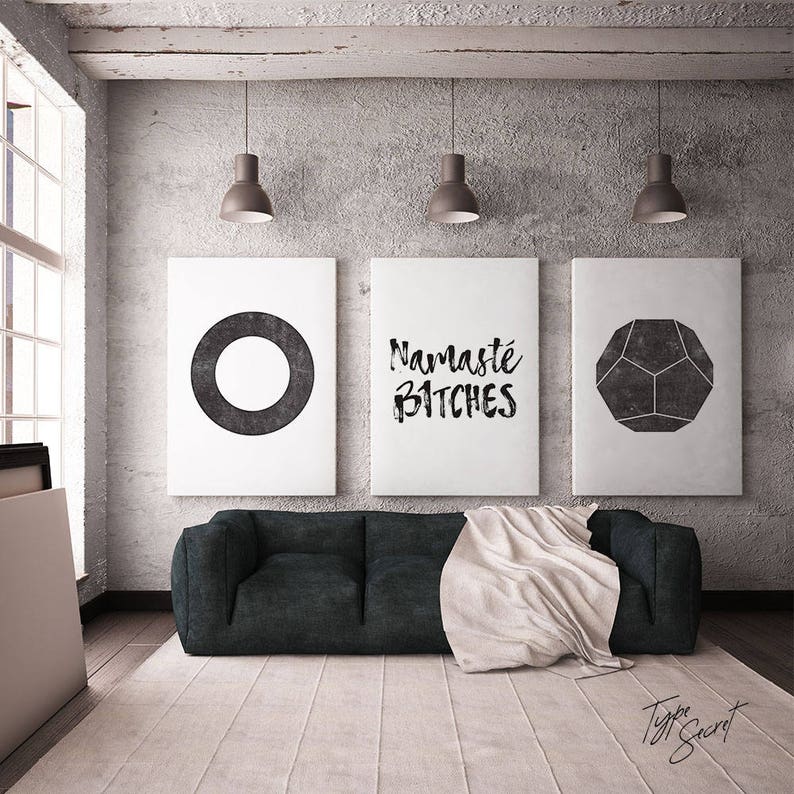 Puede incluir: Tres impresiones de arte minimalistas en blanco y negro con una forma geom&eacute;trica, la palabra "Namaste Bitches" y un c&iacute;rculo. Las impresiones est&aacute;n colgadas en una pared de hormig&oacute;n gris sobre un sof&aacute; negro con una manta blanca.