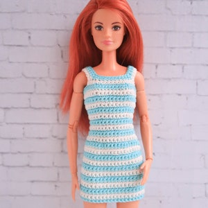 May include: A red-haired doll wearing a blue and white striped crochet dress. The dress has a sleeveless design and a fitted silhouette.