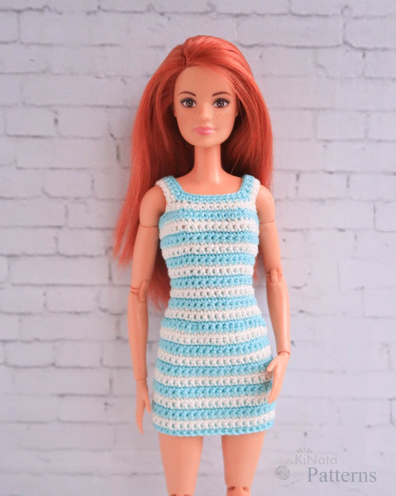 May include: A red-haired doll wearing a blue and white striped crochet dress. The dress has a sleeveless design and a fitted silhouette.