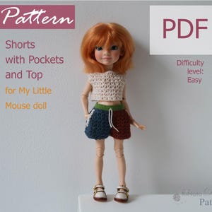 May include: A doll dressed in a crocheted top and shorts. The top is beige, and the shorts are blue, green, and brown. The image includes the text "Pattern," "Shorts with Pockets and Top for My Little Mouse doll," and "PDF."