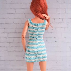 May include: A blue and white striped crochet dress with a button closure down the back. The dress is made for a doll.