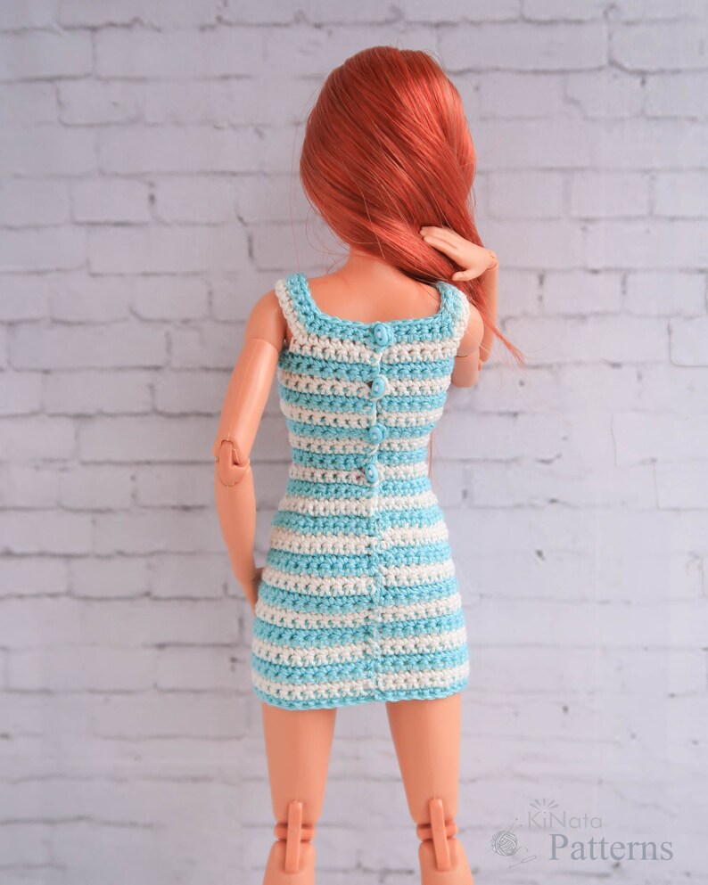 May include: A blue and white striped crochet dress with a button closure down the back. The dress is made for a doll.