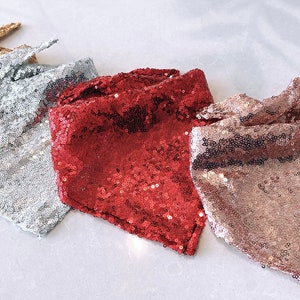 Può includere: Quattro bandane con paillettes in oro, argento, rosso e oro rosa. Ogni bandana è quadrata con un nodo in alto. Le paillettes creano un effetto scintillante, ideale per le feste o per aggiungere un tocco di glamour.